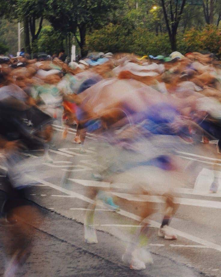 Foule de coureurs en mouvement traversant une rue parisienne au départ d'une course.